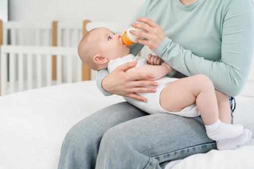 膝の上で抱っこされミルクを飲んでいる赤ちゃん 膝の上で抱っこされミルクを飲んでいる赤ちゃん 赤ちゃん,哺乳瓶,飲むの写真素材