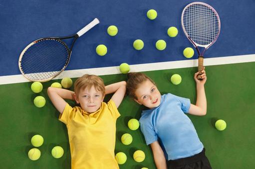 ボールとラケット横でくつろぐ男の子と女の子 男女,子供,外国人の写真素材