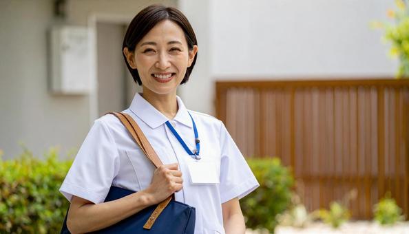 訪問看護で訪問先の住宅に笑顔で立つ女性 訪問看護で訪問先の住宅に笑顔で立つ女性の写真