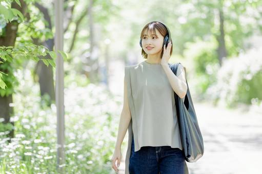 新緑の中ヘッドフォンで音楽を聴く若い女性 新緑の中ヘッドフォンで音楽を聴く若い女性 女性,外出,ヘッドフォンの写真素材