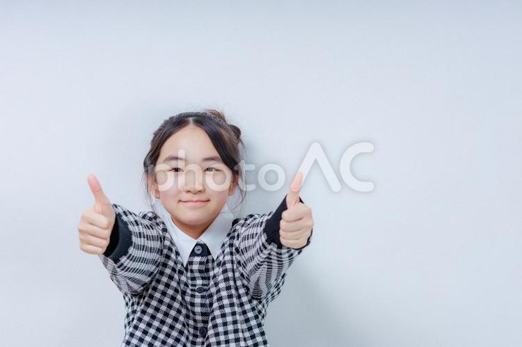 両手でグッドサインを出す笑顔の女の子 女性,小学生,少女の写真素材