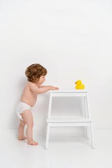 Baby in diapers staring at duck toy, JPG