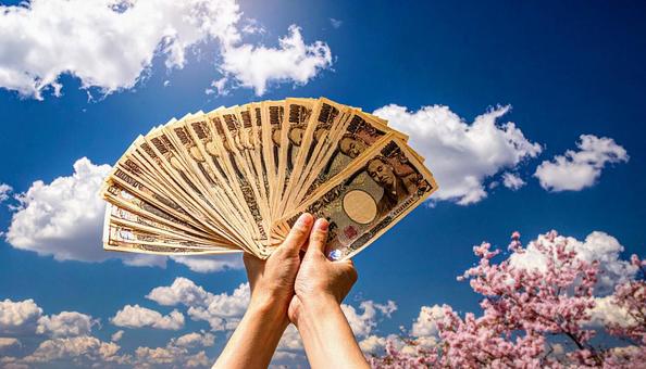 一万円を持つ手 青空背景 一万円を持つ手 青空背景の写真