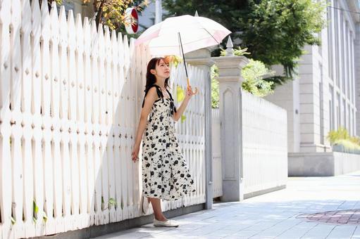 白い塀にもたれて景色を眺める女性 白い塀にもたれて景色を眺める女性 女性,美人,日傘の写真素材