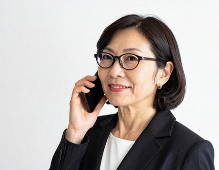 携帯電話で通話する40代キャリアウーマン 携帯電話で通話する40代キャリアウーマンの写真