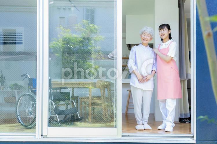 窓際でシニア女性を介護をする介護士の女性 介護,介護士,シニアの写真素材
