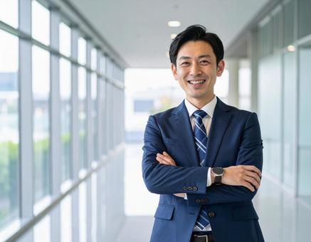 オフィス廊下で腕を組み笑顔のビジネスマン オフィス廊下で腕を組み笑顔のビジネスマンの写真