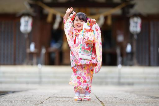 神社の参道で元気いっぱいに手を挙げる女の子 神社の参道で元気いっぱいに手を挙げる女の子の写真