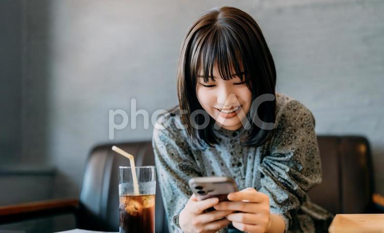 ソファに座ってスマホを使う若い女性 女性,スマホ,スマートフォンの写真素材