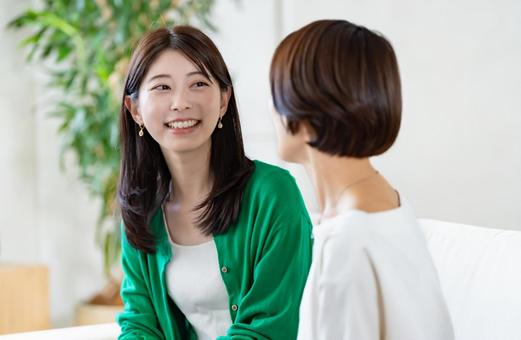 ソファに座り会話をする女性 ソファに座り会話をする女性の写真