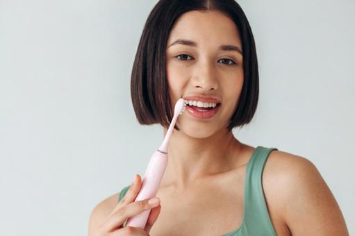 電動歯ブラシで縦磨きする女性 電動歯ブラシで縦磨きする女性の写真