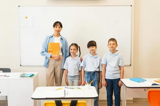 肩を組んで記念撮影する先生と生徒 女性,女の子,男の子の写真素材