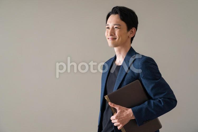 パソコンを持つジャケットを着た男性 ビジネス,ビジネスマン,仕事の写真素材