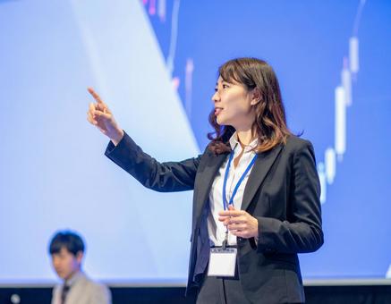 ステージ上でプレゼンをする女性 ステージ上でプレゼンをする女性の写真
