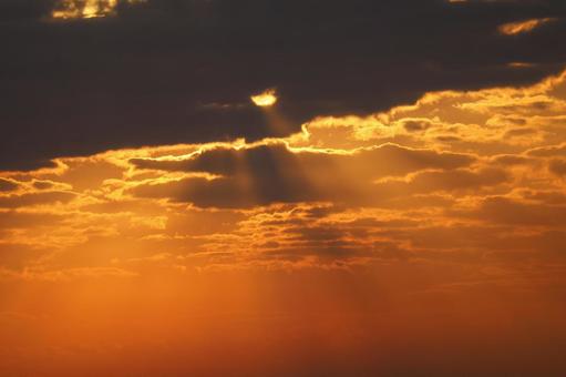 オレンジ色の夕空と太陽と黒い雲の空の風景の写真