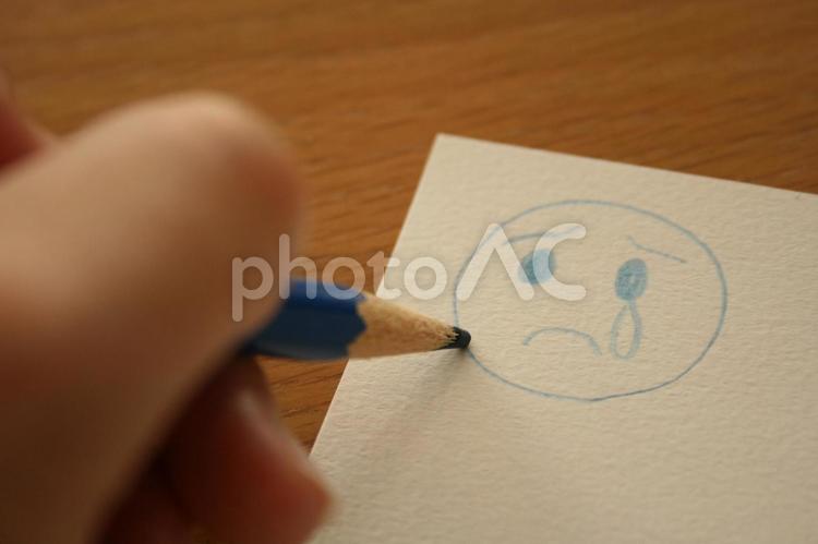 悲しい顔の絵を描く女性の手 小物,雑貨,色鉛筆の写真素材