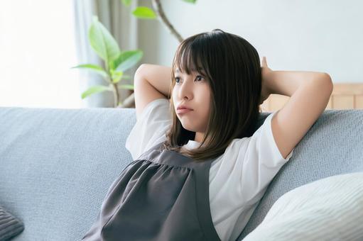 リビングのソファに座って考える女性 リビングのソファに座って考える女性 女性,考える,困るの写真素材