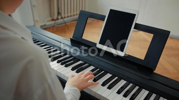 譜面台にタブレットを置いてキーボードを練習する人の手元 キーボード,鍵盤,手元の写真素材
