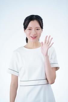 女性が手を挙げて挨拶する 女性,笑顔,手をあげるの写真素材