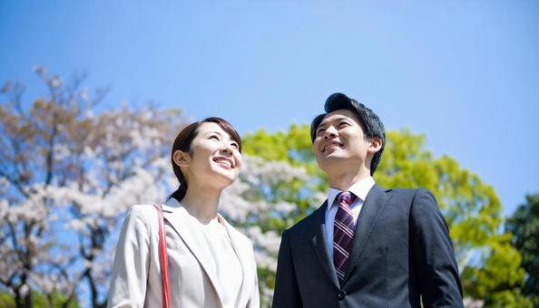 青空の下、遠くを見つめる若いスーツの男女 青空の下、遠くを見つめる若いスーツの男女の写真