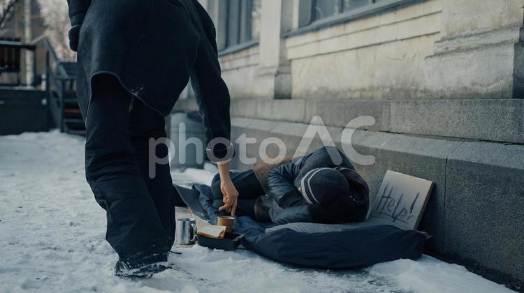 寝ているホームレスと横を歩く人 男性,ニット帽,人物の写真素材