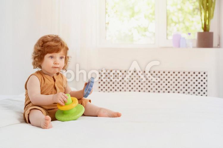 玩具を持ちベッドに座っている赤ちゃん 赤ちゃん,玩具,持つの写真素材