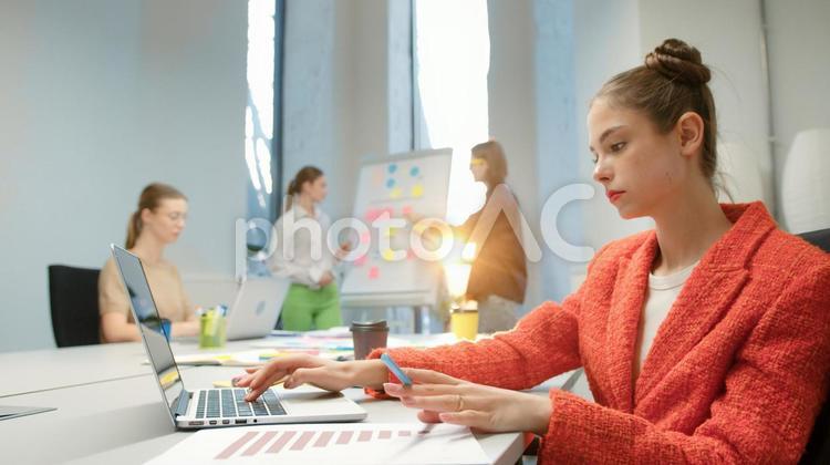 ノートパソコンを使っている女性と会議中の男女 ビジネス,ビジネスマン,ビジネスウーマンの写真素材