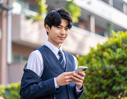 スマホを操作する男子高校生 スマホを操作する男子高校生の写真