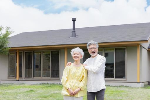 笑顔で住宅の前に立つシニア夫婦 笑顔で住宅の前に立つシニア夫婦の写真