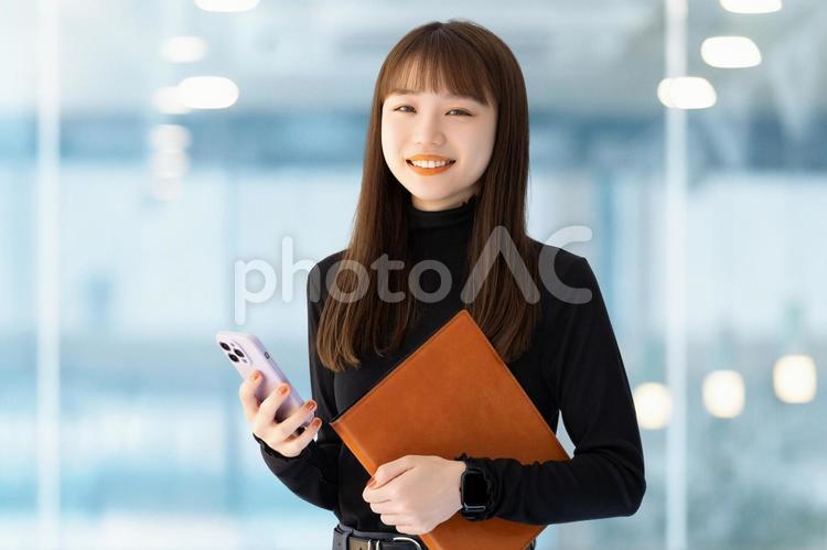 スマホとバインダーを持つ笑顔の女性 女性,スマホ,笑顔の写真素材