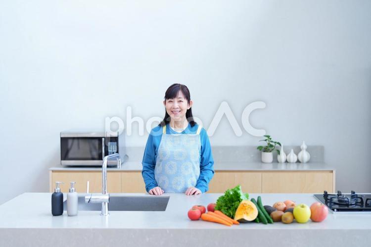キッチンに立つエプロン姿の女性と新鮮な野菜 主婦,家政婦,エプロンの写真素材