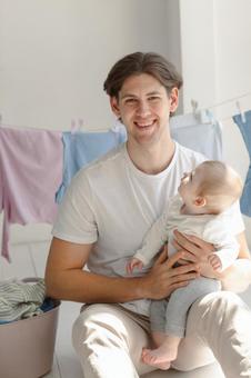 赤ちゃんを抱っこしてにっこりする男性 赤ちゃんを抱っこしてにっこりする男性 親子,男性,抱っこの写真素材