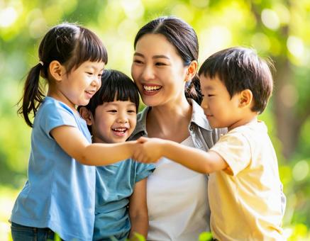 新緑の中で遊ぶ3人の子供と母親 新緑の中で遊ぶ3人の子供と母親の写真