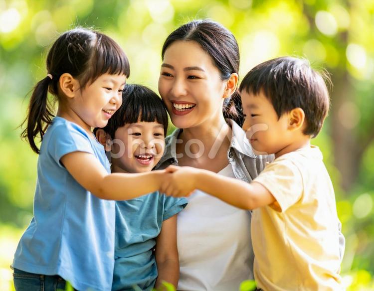 新緑の中で遊ぶ3人の子供と母親 親子,母娘,家族の写真素材