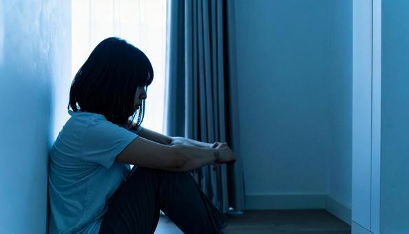 部屋で落ち込んで座る日本人女性の横顔 部屋で落ち込んで座る日本人女性の横顔の写真