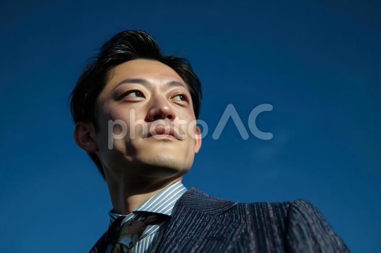 青空を見つめるスーツ姿の若い日本人男性 青空,若い,スーツの写真素材