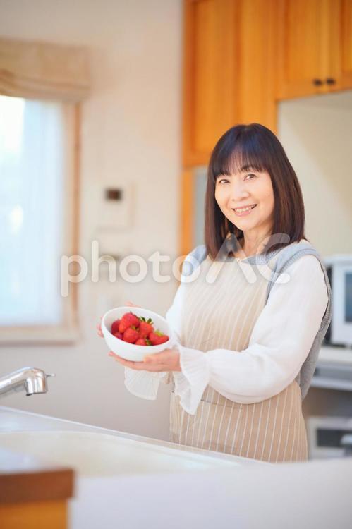 キッチンでいちごの入った器を持つ女性 女性,日本人,50代の写真素材