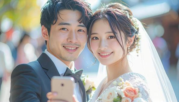 スマホで自撮りする花嫁花婿 スマホで自撮りする花嫁花婿の写真