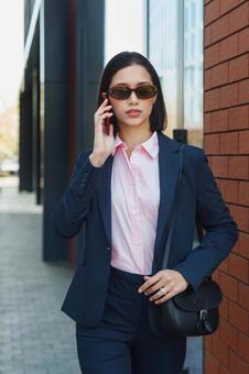オフィスビルの外でスマートフォンで電話するサングラスを掛けたビジネスウーマン ビジネスウーマン,ビジネス,女性の写真素材
