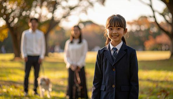 公園の芝生に立つ制服の子供と両親と愛犬の写真
