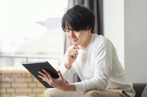 A man using a tablet in his living room, tablet, male, living, JPG