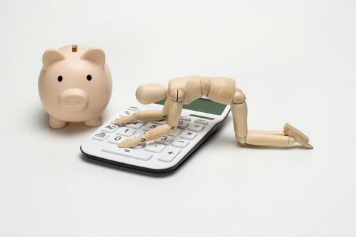 電卓に膝をつくデッサン人形と豚の貯金箱 電卓,お金,貯金の写真素材