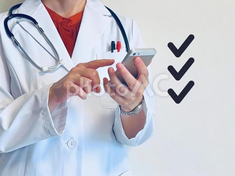 スマホでやることをチェックする女医 スマホ,チェック,タスクの写真素材