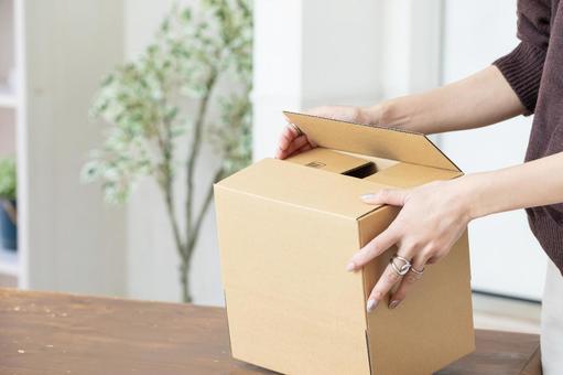 段ボールで荷造りする手元 段ボールで荷造りする手元の写真