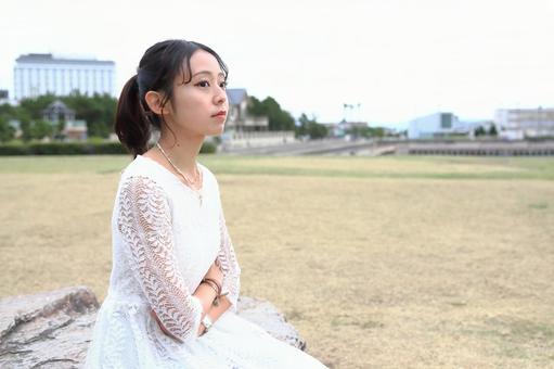 広場に座り遠くを見る女性 女性,座る,広場の写真素材