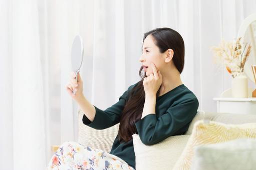Woman checking her skin in the mirror, JPG Woman checking her skin in the mirror, JPG