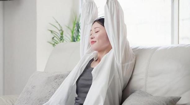 ソファで伸びをするアジア人女性 女性,伸び,ストレッチの写真素材