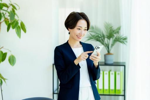 スマホを持つビジネスウーマン スマホを持つビジネスウーマン スマホ,ビジネスウーマン,キャリアウーマンの写真素材