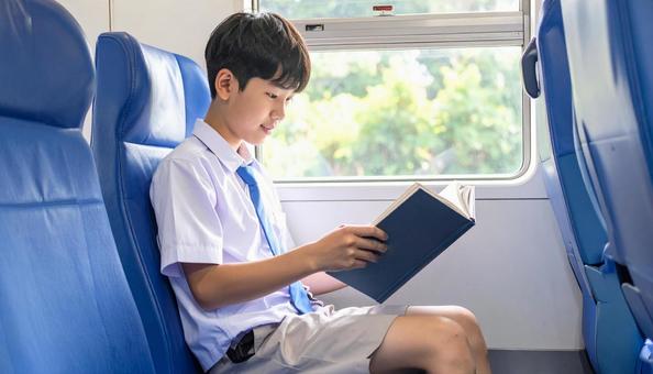 電車内で読書する男子学生 電車内で読書する男子学生の写真