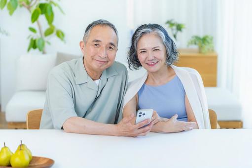 リビングでスマホを見るシニア夫婦 リビングでスマホを見るシニア夫婦 スマホ,笑顔,シニアの写真素材